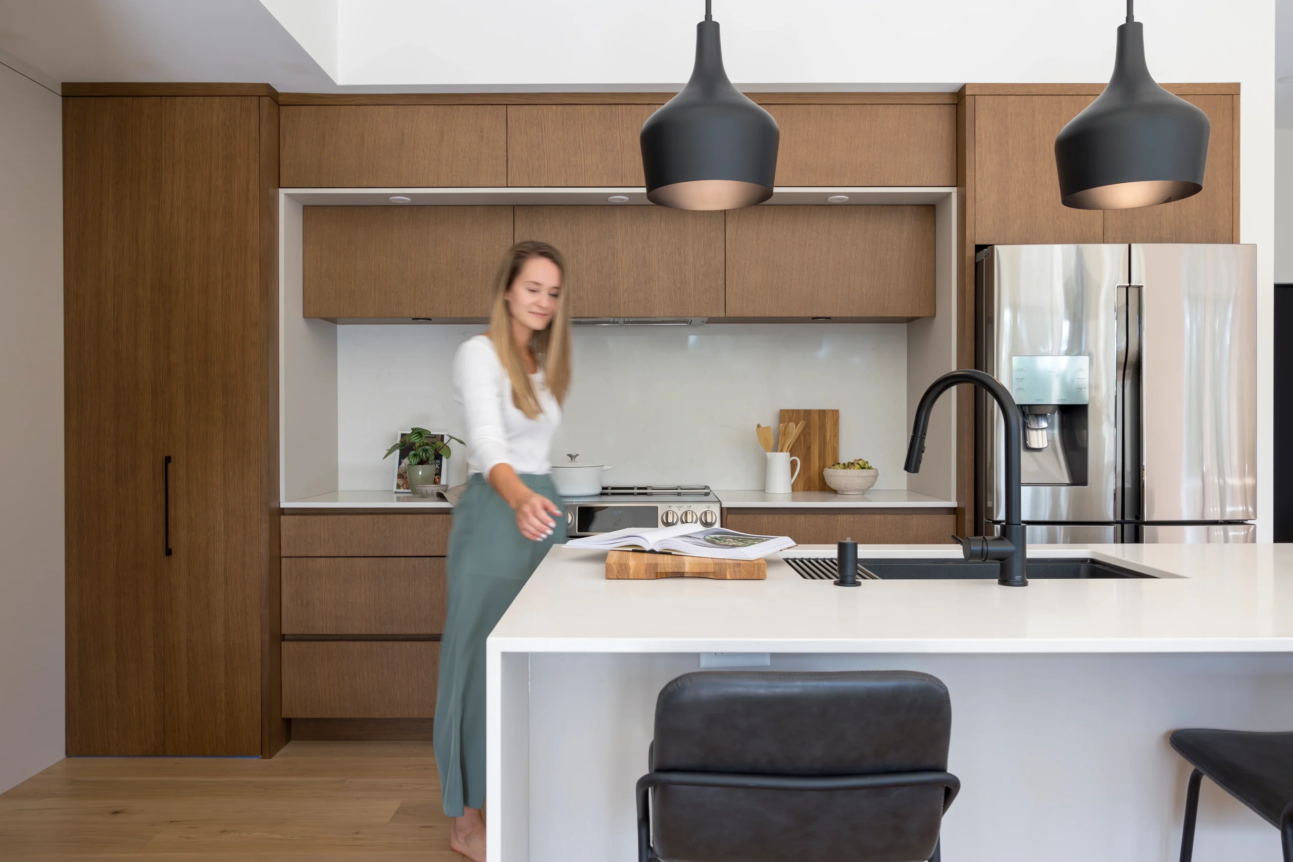 Contemporary kitchen with wood cabinets, white island and black light fixtures, designed for ergonomic daily use.