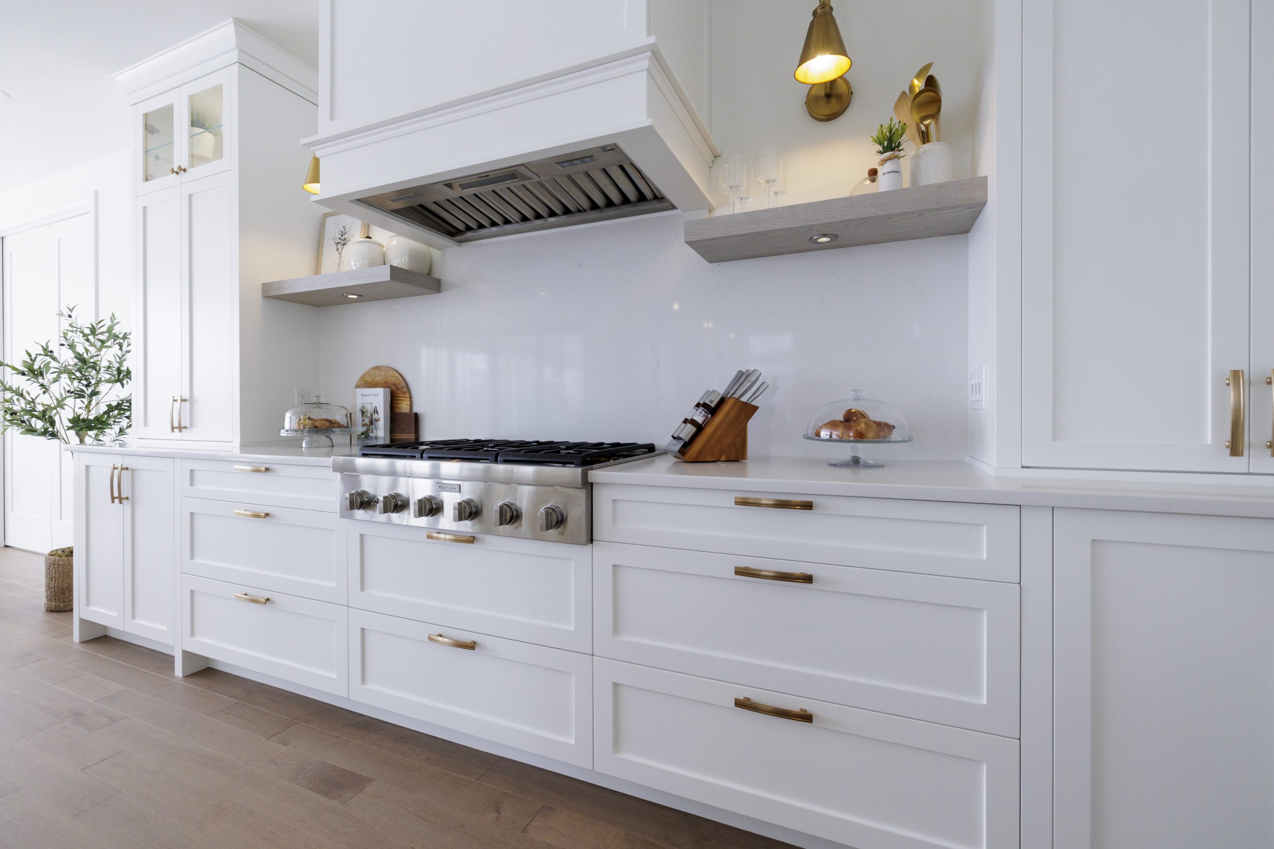 White linear kitchen with a central hood and continuous work surface, ideal for optimizing small spaces.