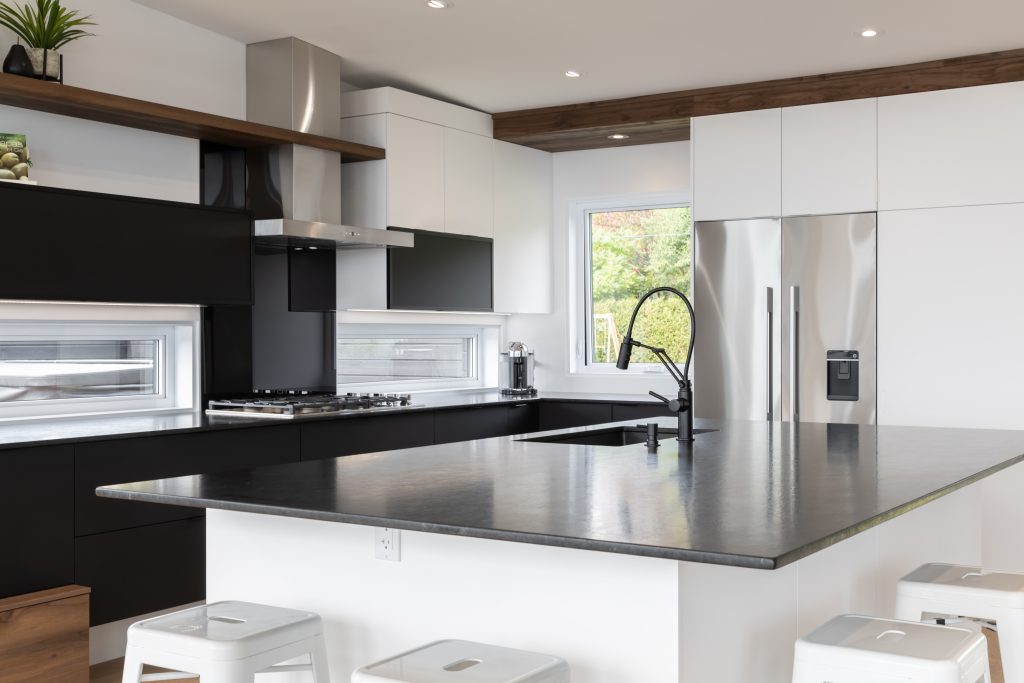 Cuisine moderne avec armoires noires et blanches, îlot sombre et électroménagers en acier inoxydable | Modern kitchen with black and white cabinets, dark island and stainless steel appliances
