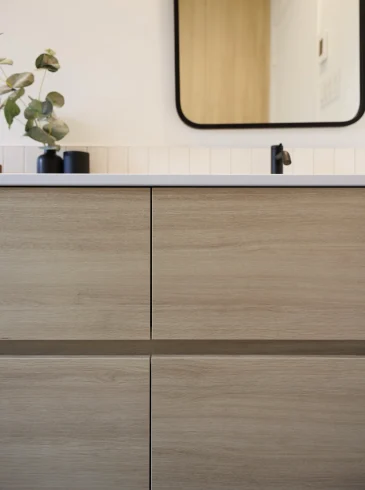 Meuble-lavabo minimaliste en bois pâle avec robinet noir mat et miroir rectangulaire aux coins arrondis | Minimalist light wood vanity with matte black faucet and rounded rectangular mirror